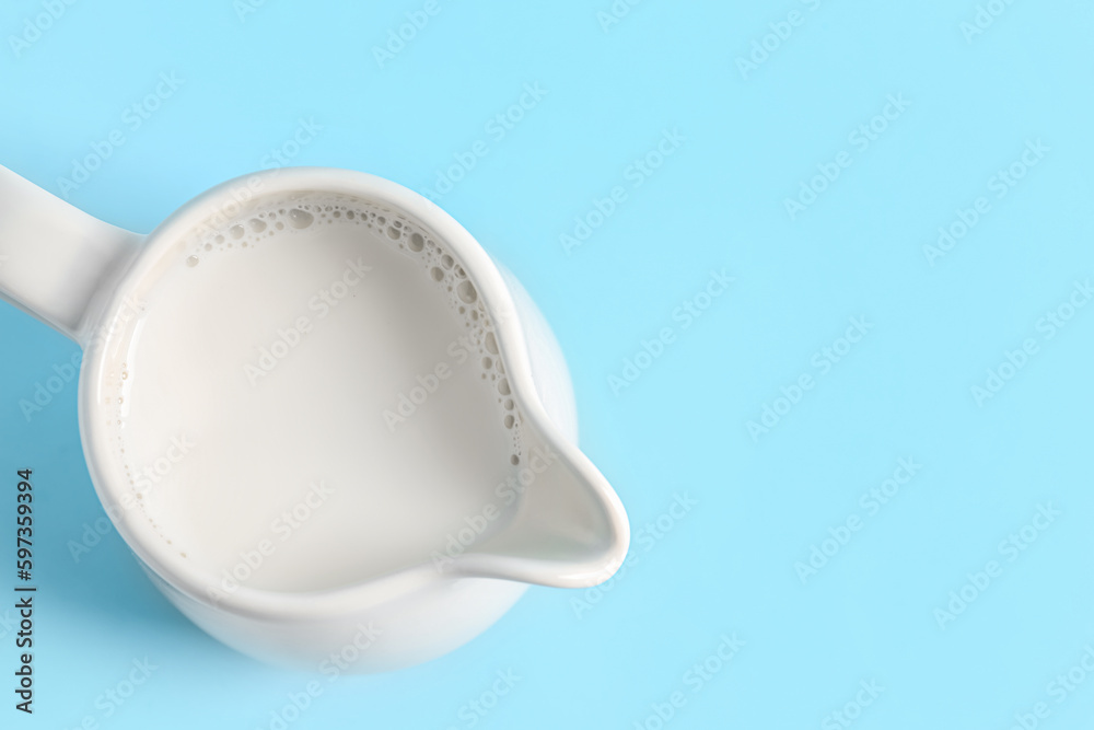 Jug with fresh milk on blue background