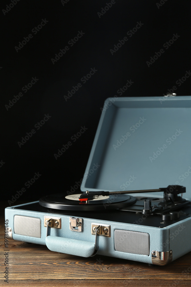 Record player with vinyl disk on dark wooden background