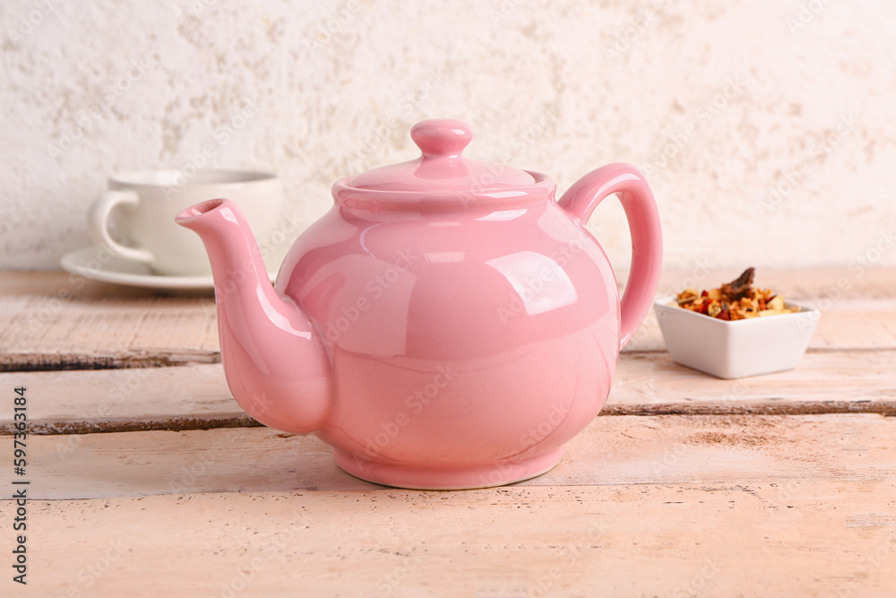 Ceramic teapot with cup of fruit tea on white wooden table