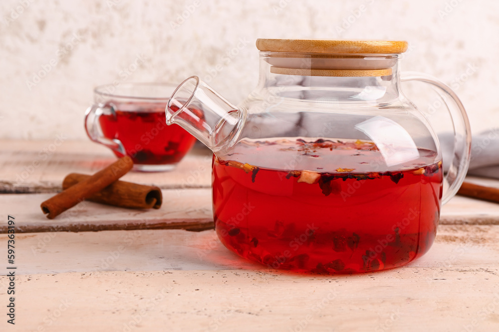 Transparent teapot and cup with fruit tea on white wooden table