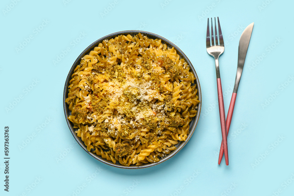 Plate of tasty Italian pasta with Parmesan cheese on blue background