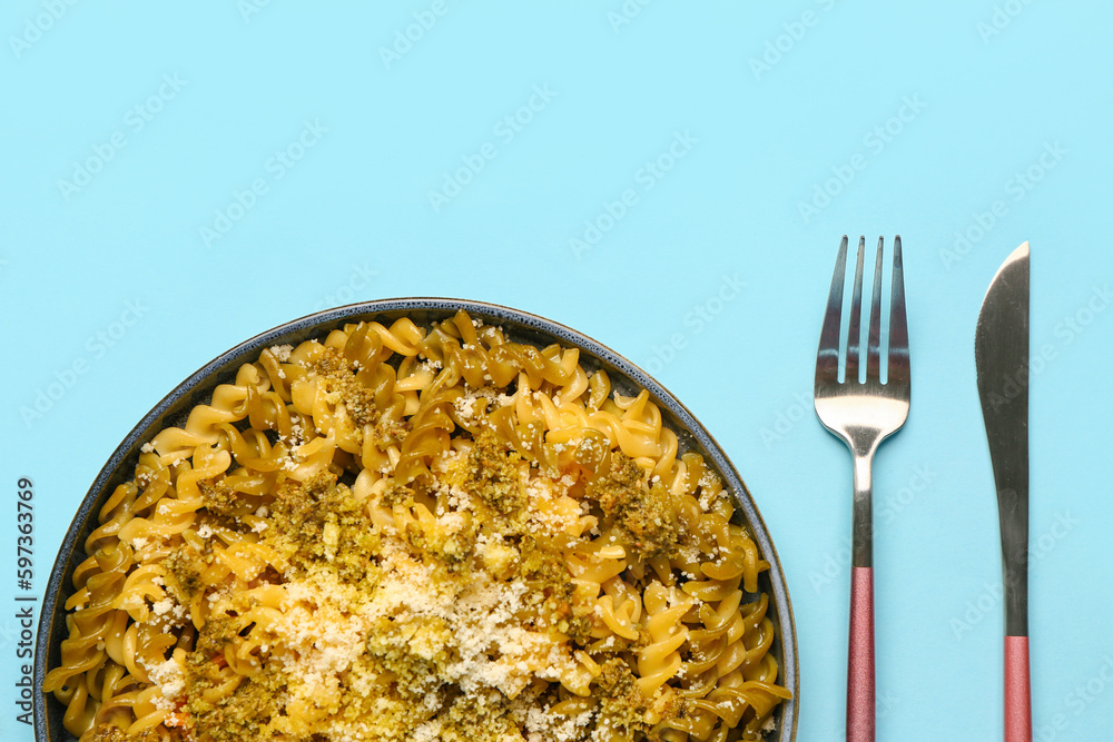 Plate of tasty Italian pasta with Parmesan cheese on blue background, closeup