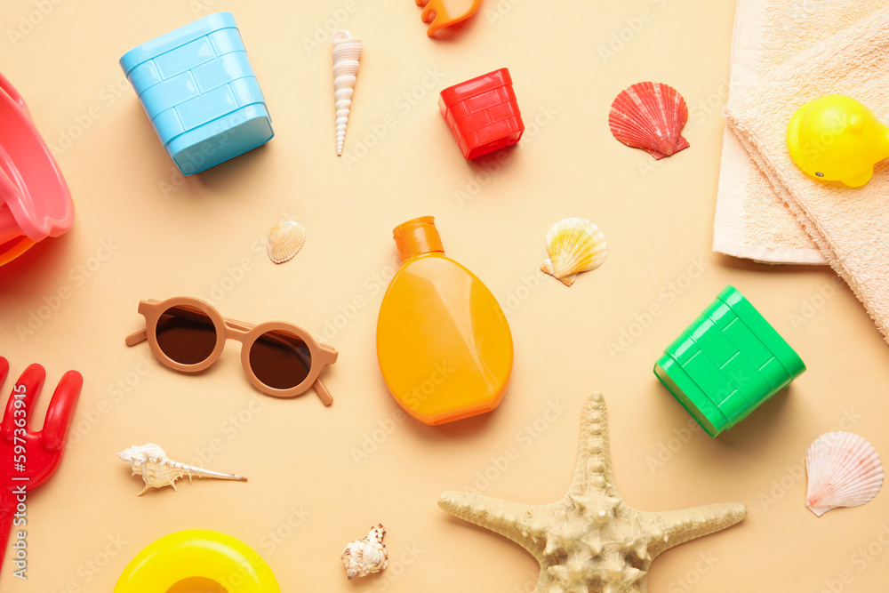 Sunscreen cream for baby with beach accessories and seashells on beige background