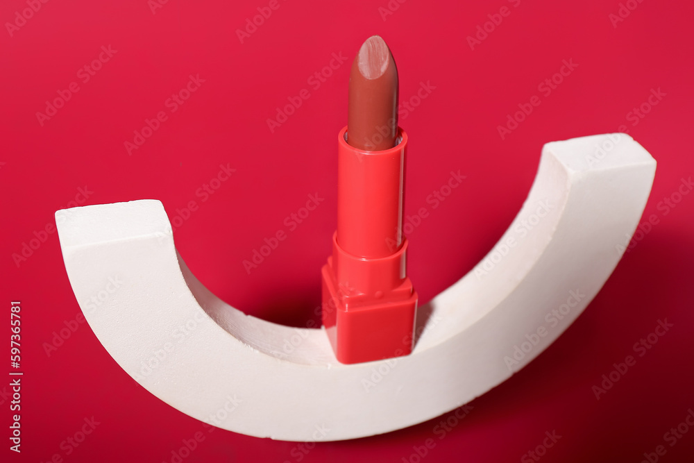 Decorative plaster podium and lipstick on red background