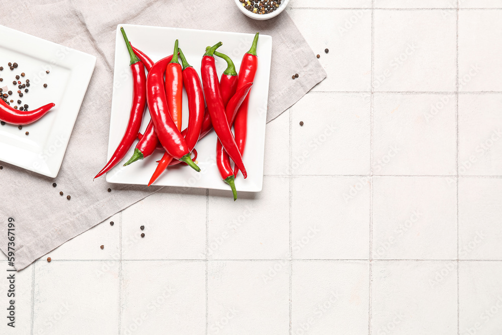 Plates with fresh chili peppers on light tile background