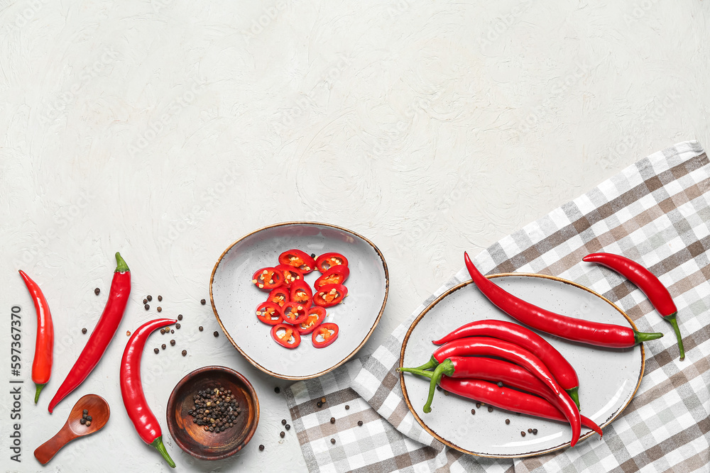 Bowl and plate with fresh chili peppers on light background