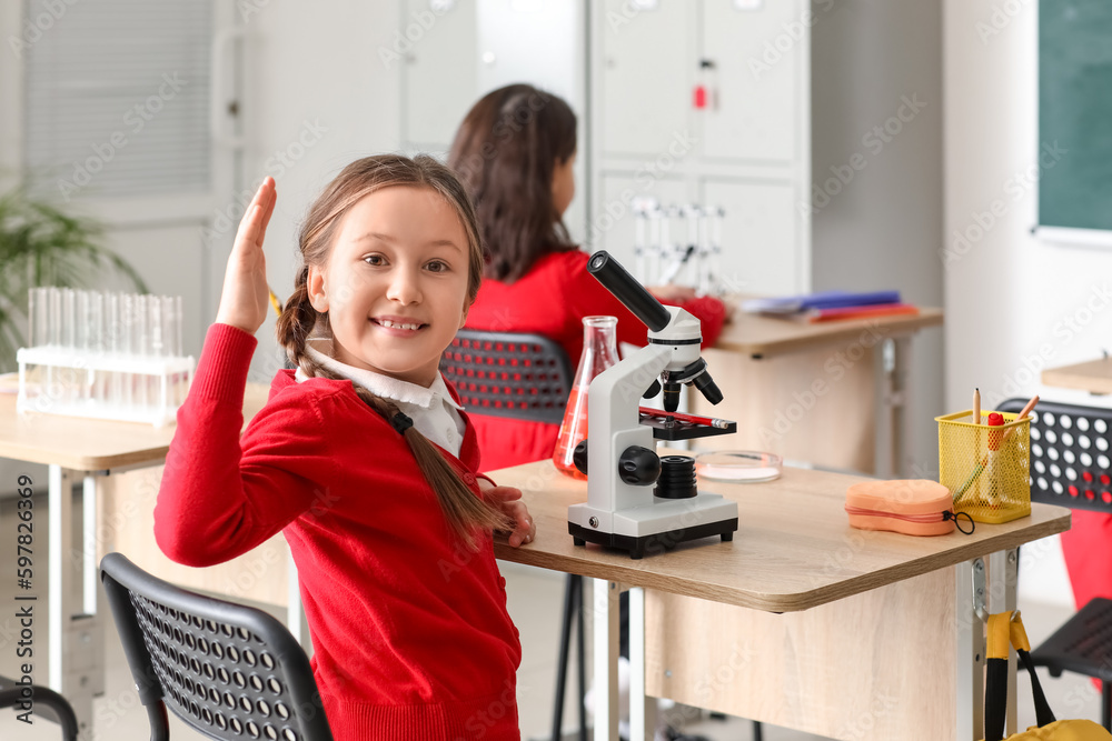 Little girl with microscope having Chemistry lesson in science classroom