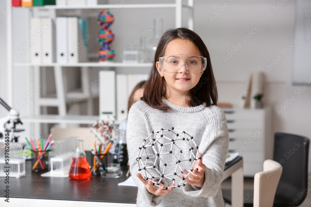 Little girl with safety goggles and molecular model in science classroom