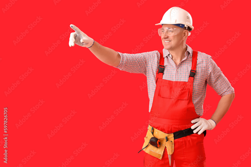 Mature carpenter in hardhat on red background