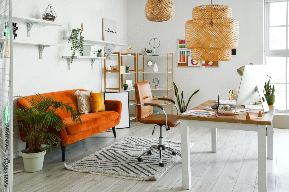 Interior of office with graphic designers workplace, shelves and sofa