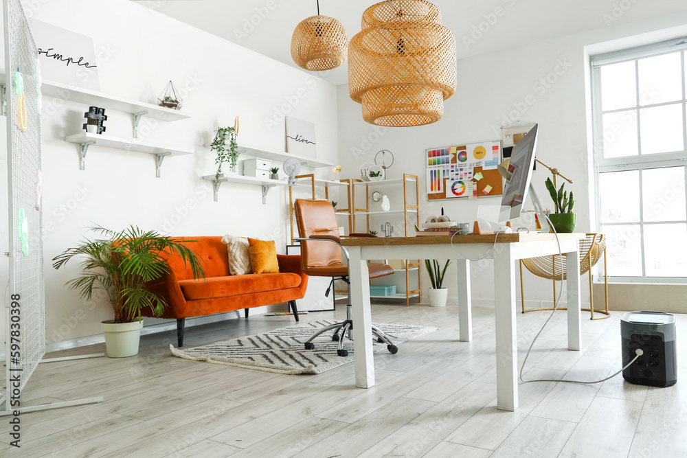 Interior of office with graphic designers workplace, shelves and sofa