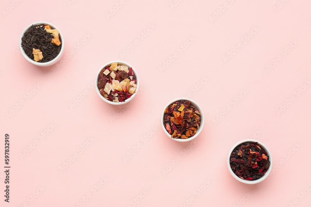 Bowls with different dried fruit tea on pink background