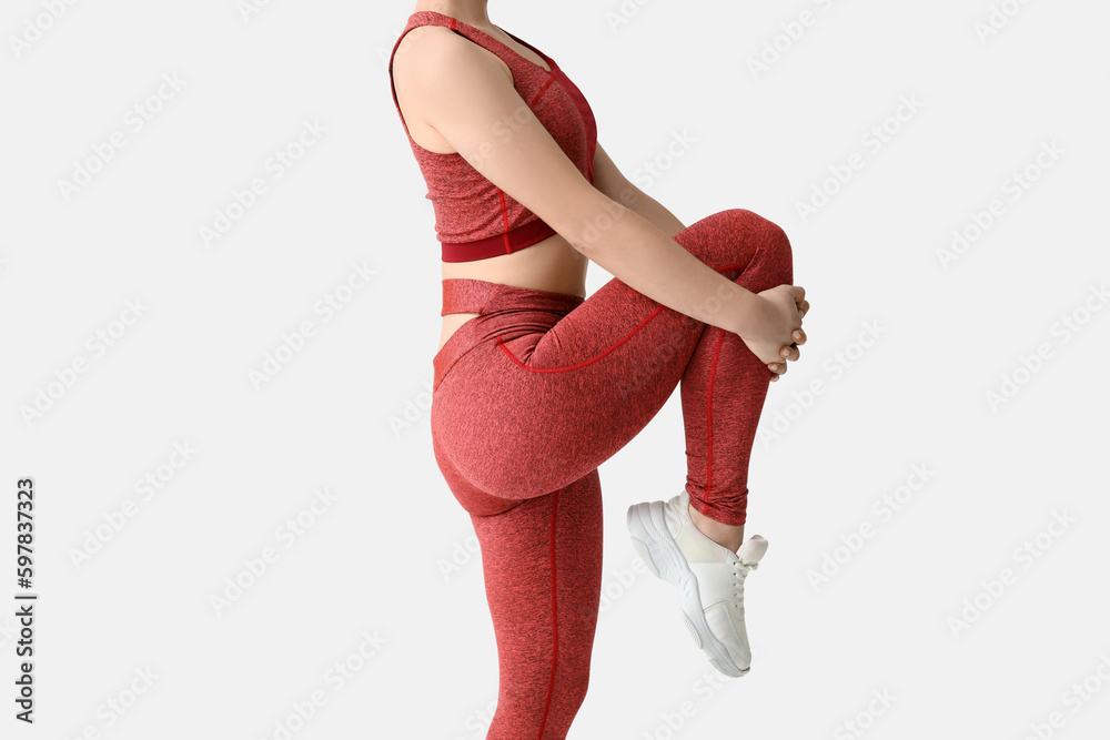 Sporty young woman in leggings on white background