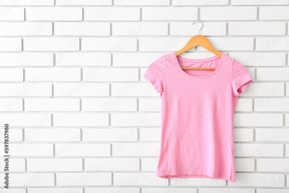 Pink t-shirt hanging on white brick wall