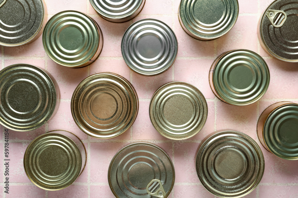 Many tin cans with fish on pink tiled table