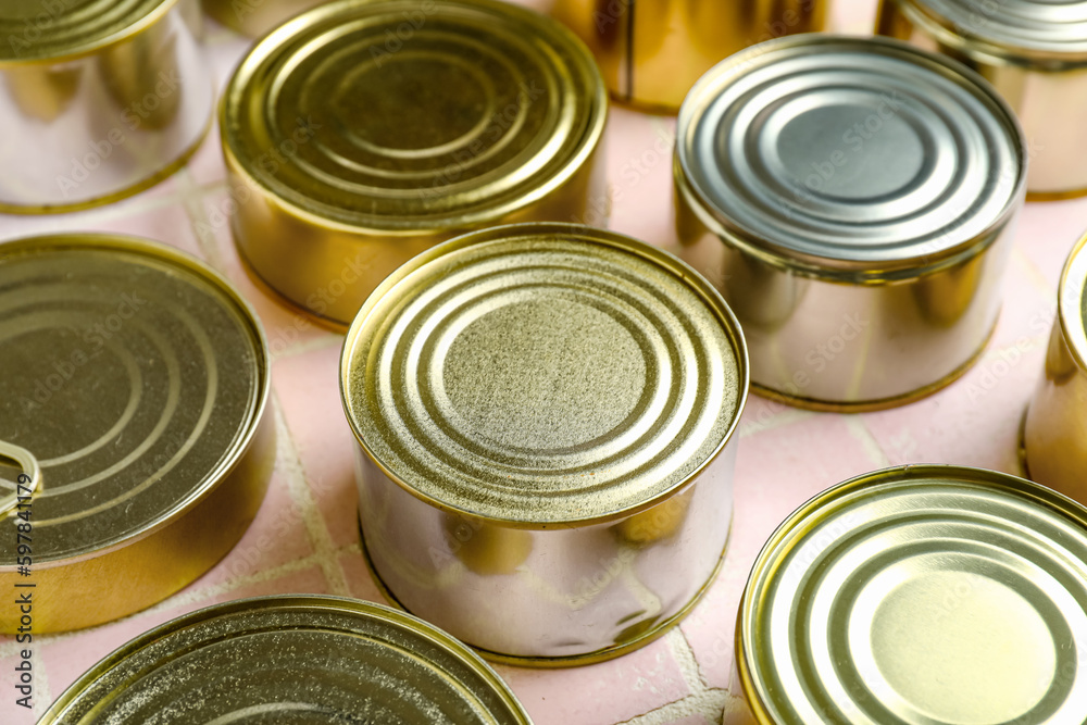 Many tin cans with fish on pink tiled table