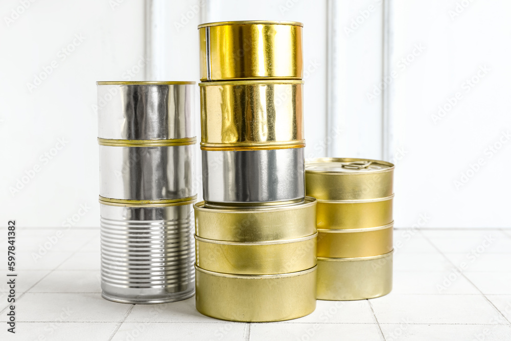 Stacks of tin cans with fish on white tiled table