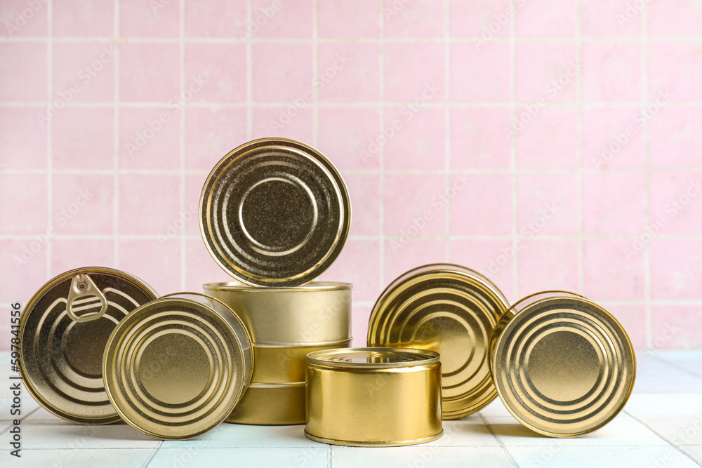 Tin cans with fish on white tiled table