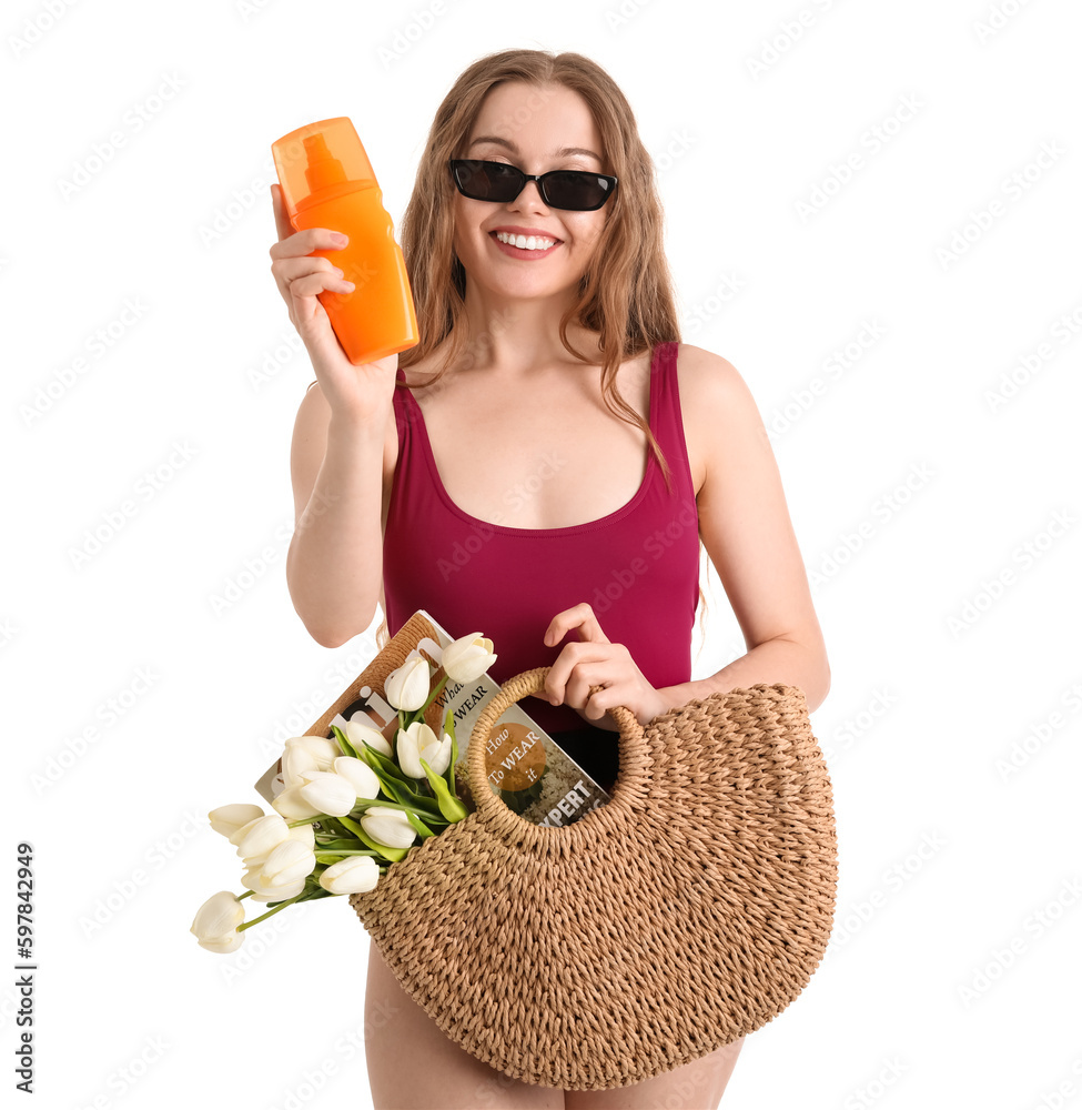 Beautiful young woman with sunscreen cream and beach bag on white background