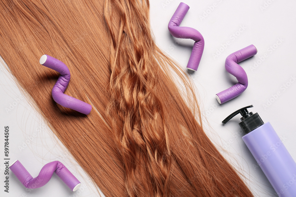 Ginger hair with curlers and bottle of cream on light background