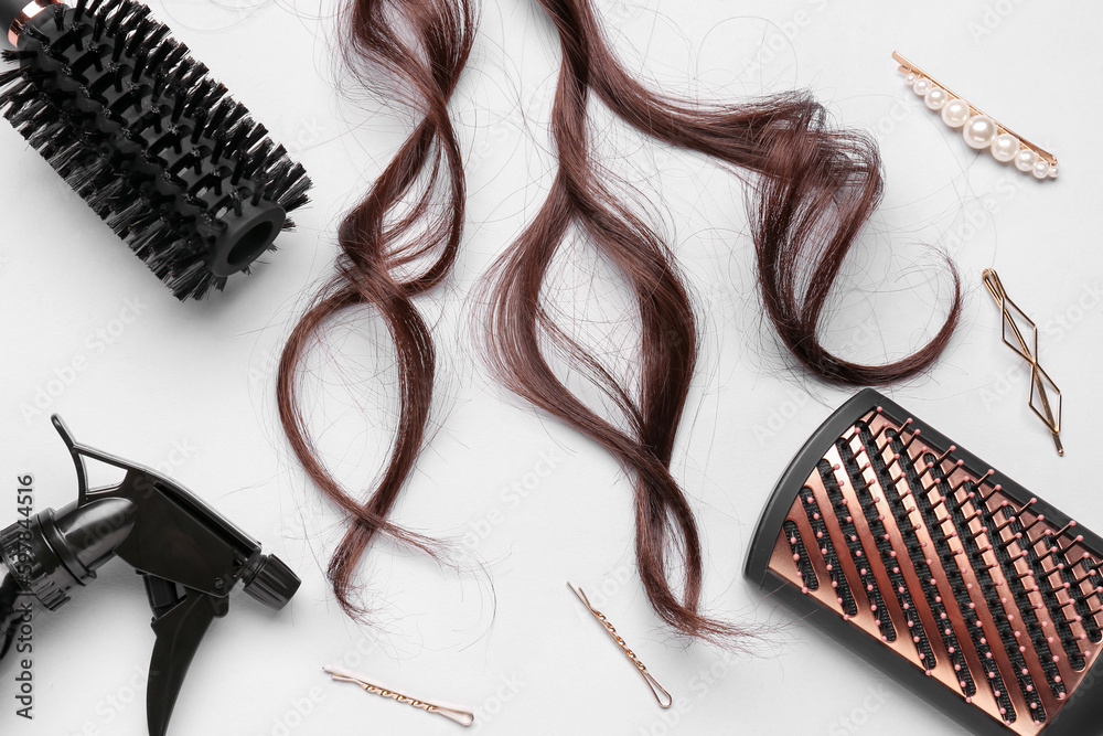 Curled brown hair with accessories on light background, closeup