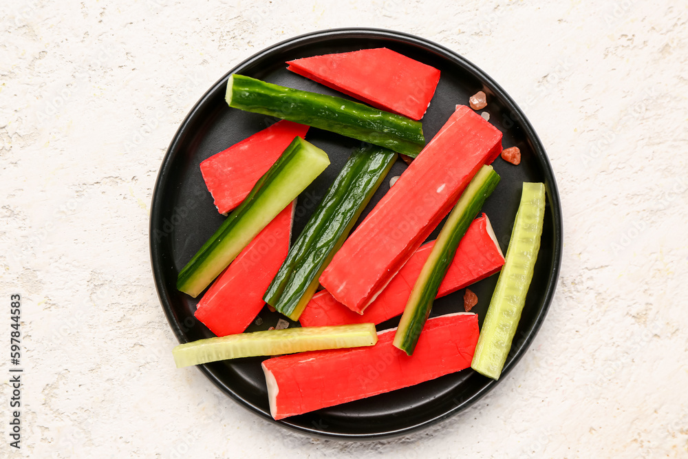 Plate with tasty crab sticks on light background