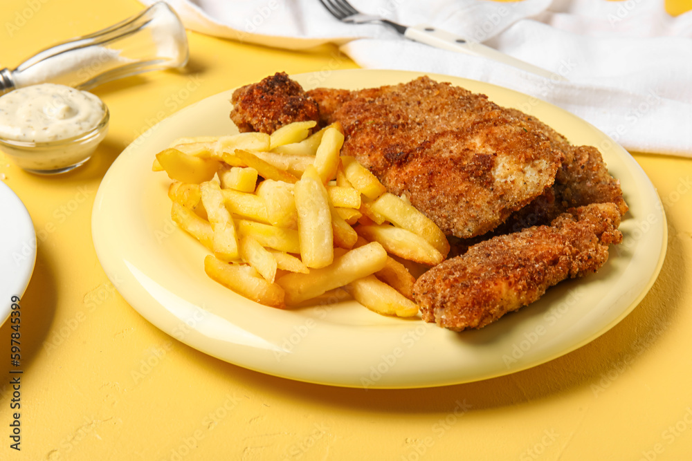 Plate of tasty fried codfish with french fries on yellow background