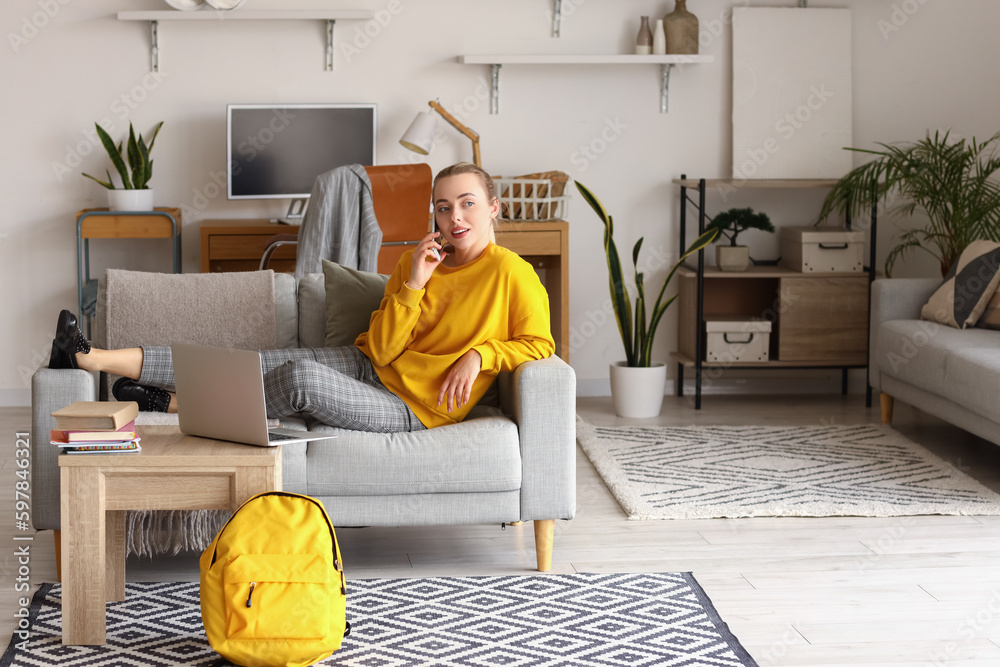 Female student talking by mobile phone on sofa at home