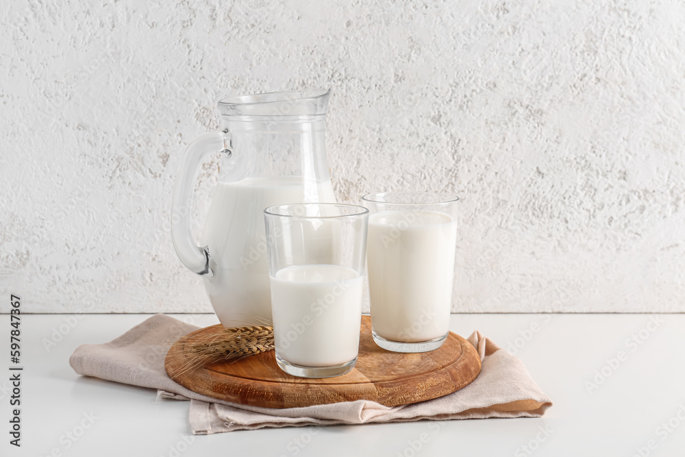 Jug and glasses with fresh milk on white background