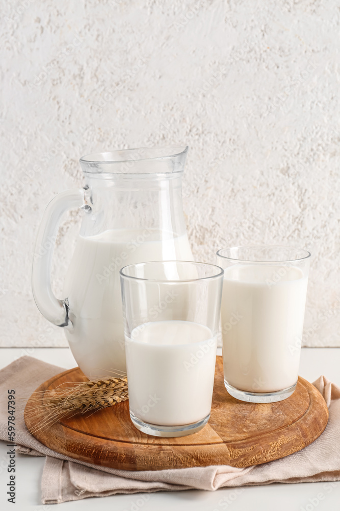 Jug and glasses with fresh milk on white background