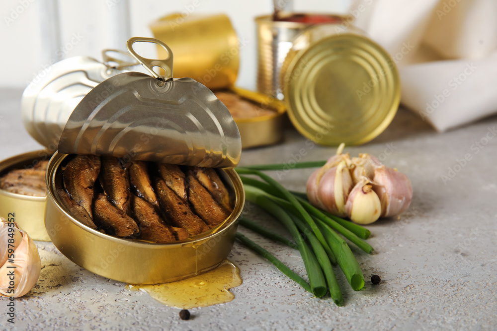 Opened tin cans with sprats in oil on grey table