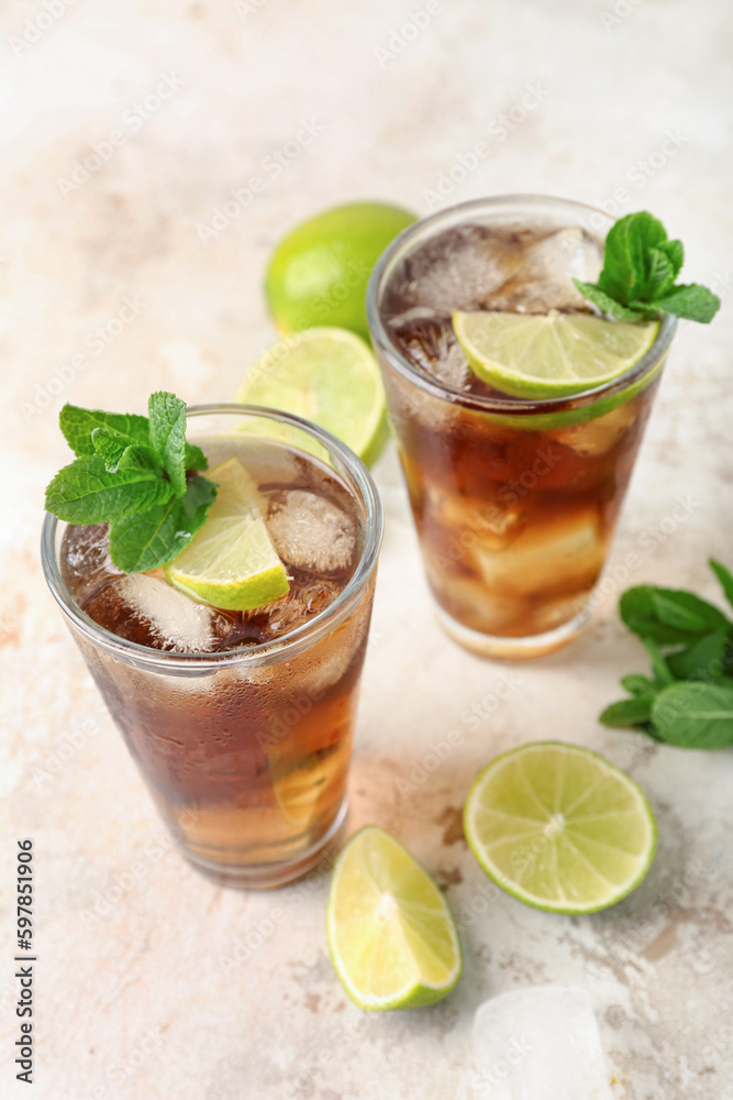 Glasses of tasty Cuba Libre cocktail on light background