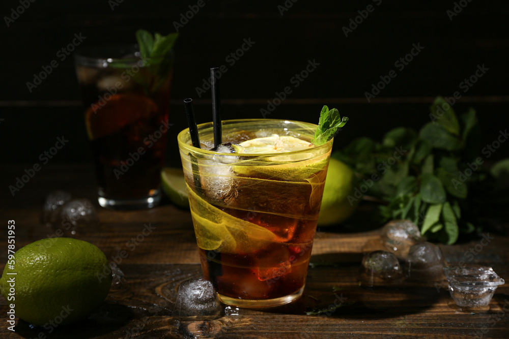 Glass of tasty Cuba Libre cocktail on dark wooden background