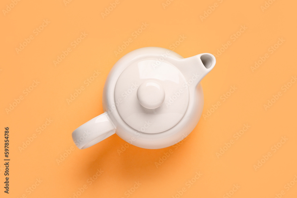 Ceramic teapot on orange background