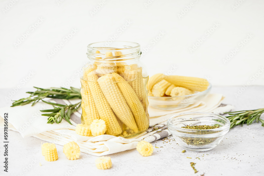 Jar with tasty canned corn cobs on light background