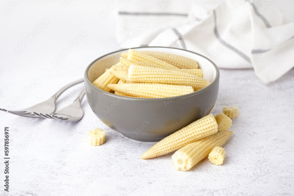 Bowl with tasty canned corn cobs on light background