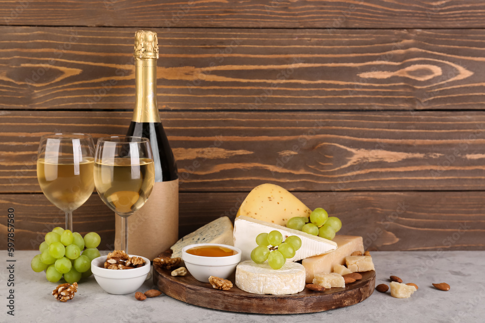 Different types of cheese with bottle and glasses of wine on table