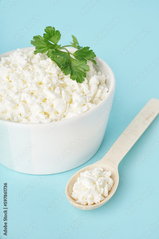 Bowl with tasty cottage cheese and parsley on blue background