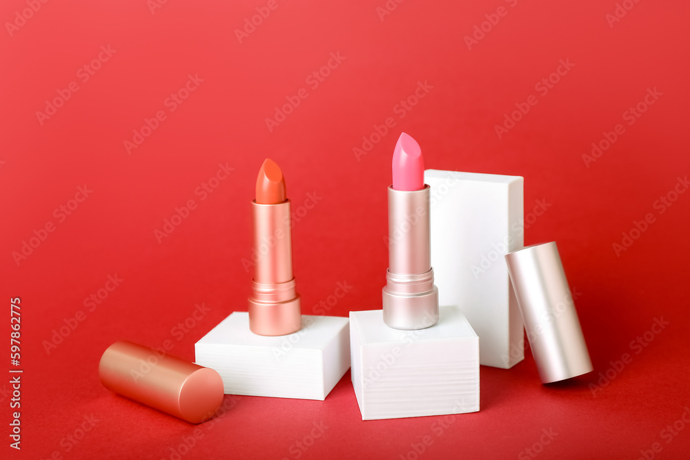 Decorative plaster podiums and lipsticks on red background