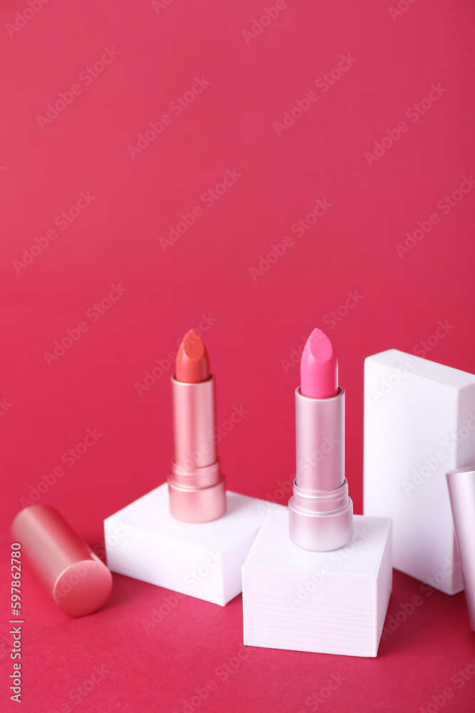 Decorative plaster podiums and lipsticks on red background