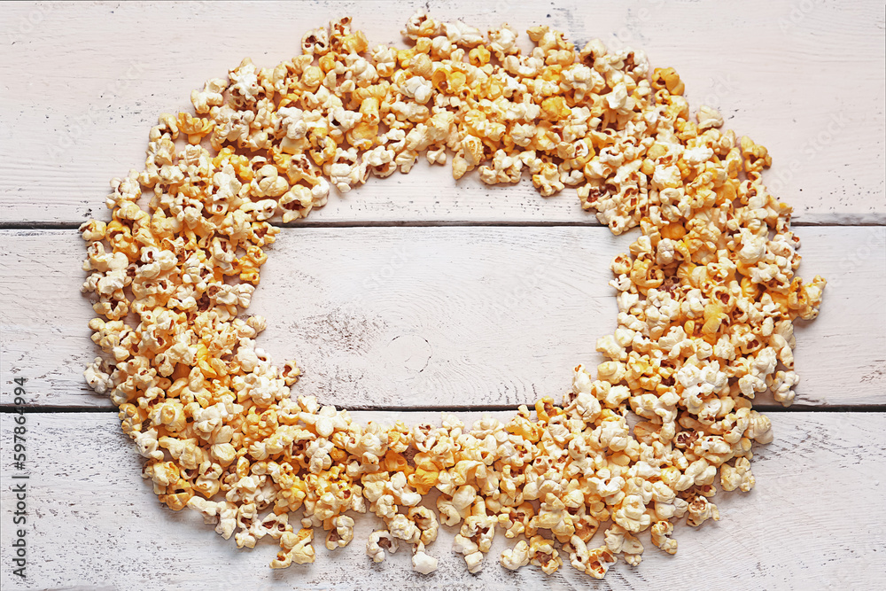 Frame made of crispy popcorn on white wooden background