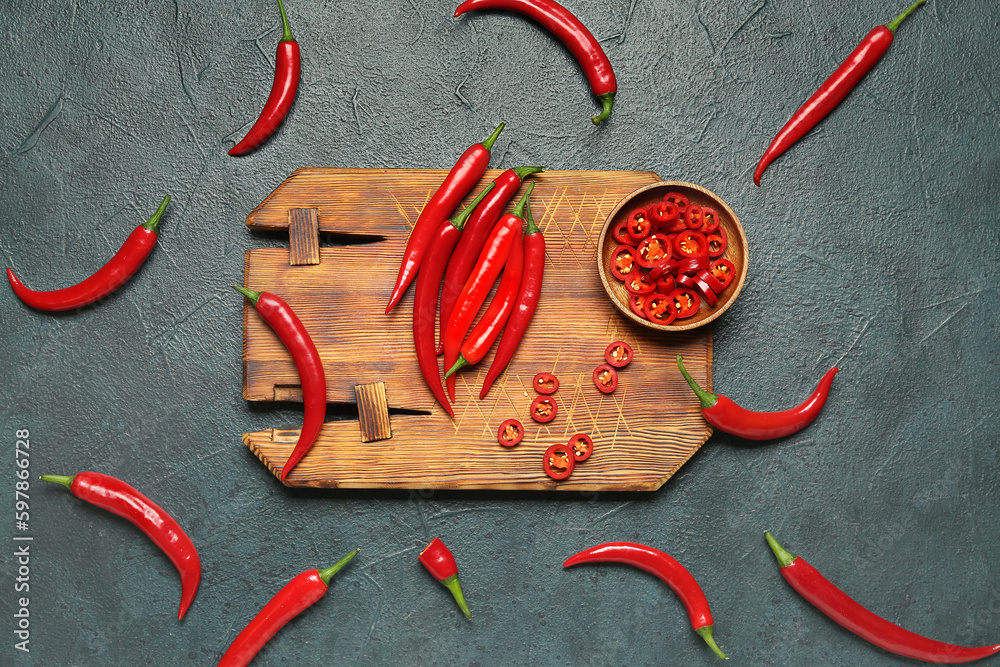 Wooden board with fresh chili peppers on dark background