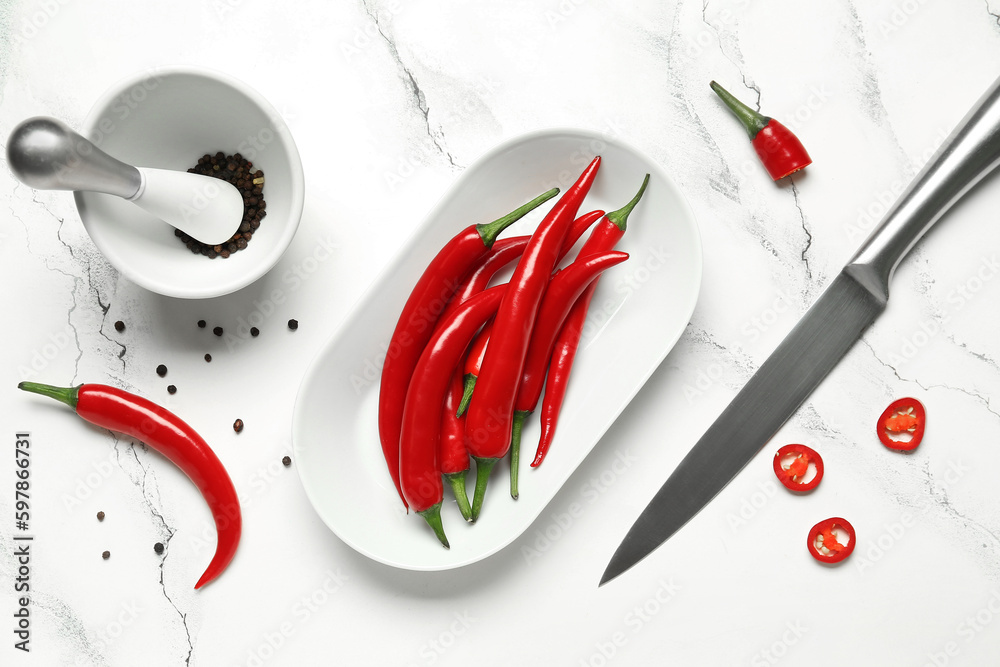 Plate with fresh chili peppers on white marble background