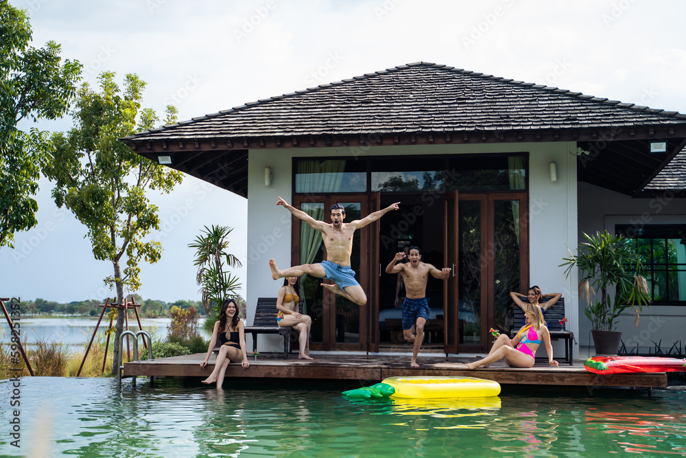 Group of diverse friend jumping into the pool, having a party together. 