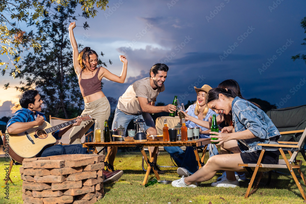 Group of diverse friend having outdoors camping party together in tent. 