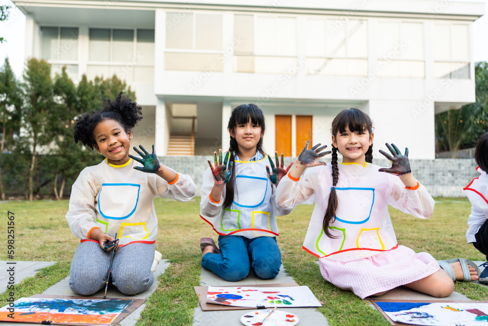 Portrait group of young student paint board outdoors in school garden. 