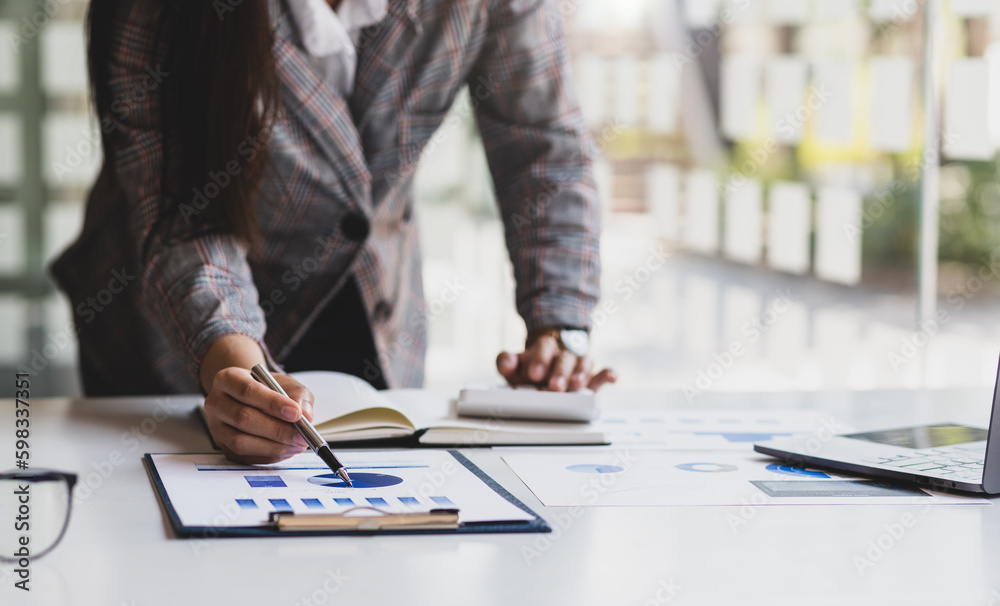 Businesswoman doing accounting work in the office analyzing charts in financial reports with a calcu