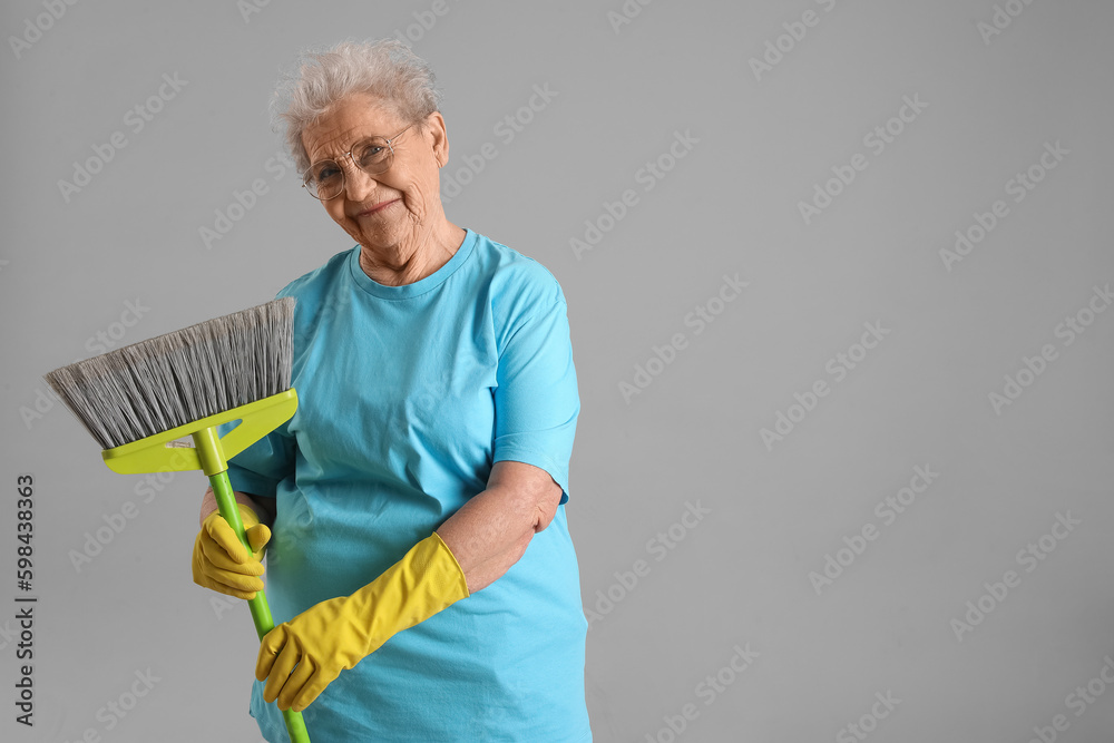 Senior woman with mop on grey background