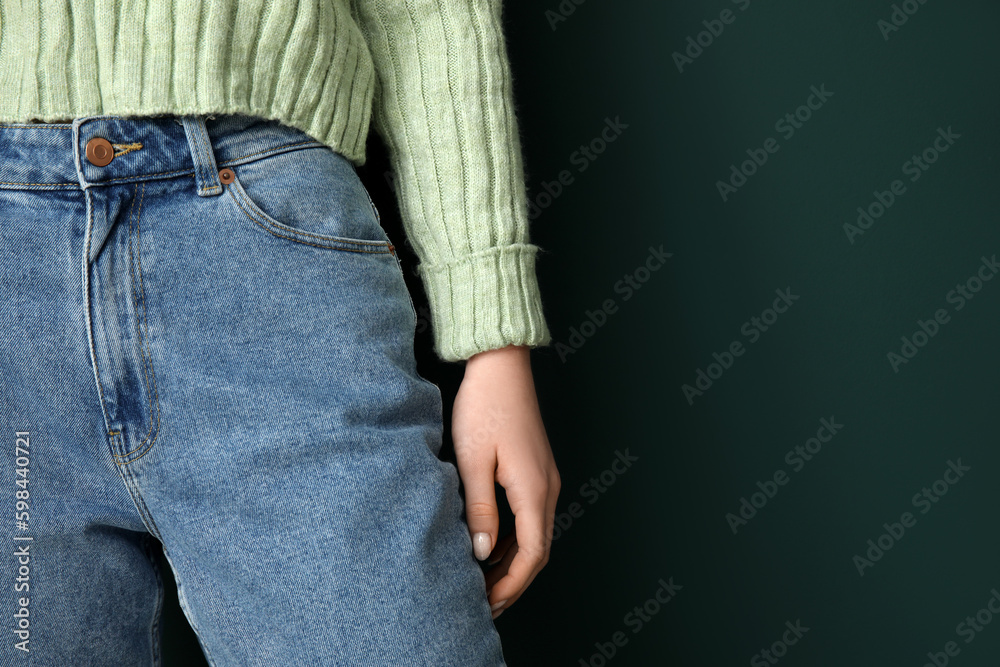 Young woman in stylish jeans on green background, closeup