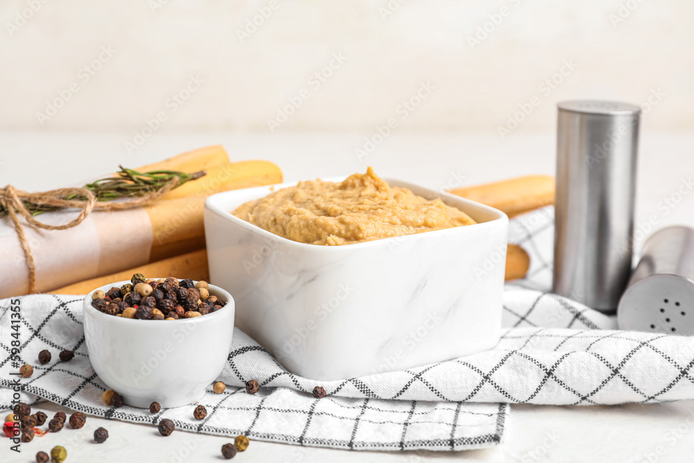 Bowl with tasty hummus on light background